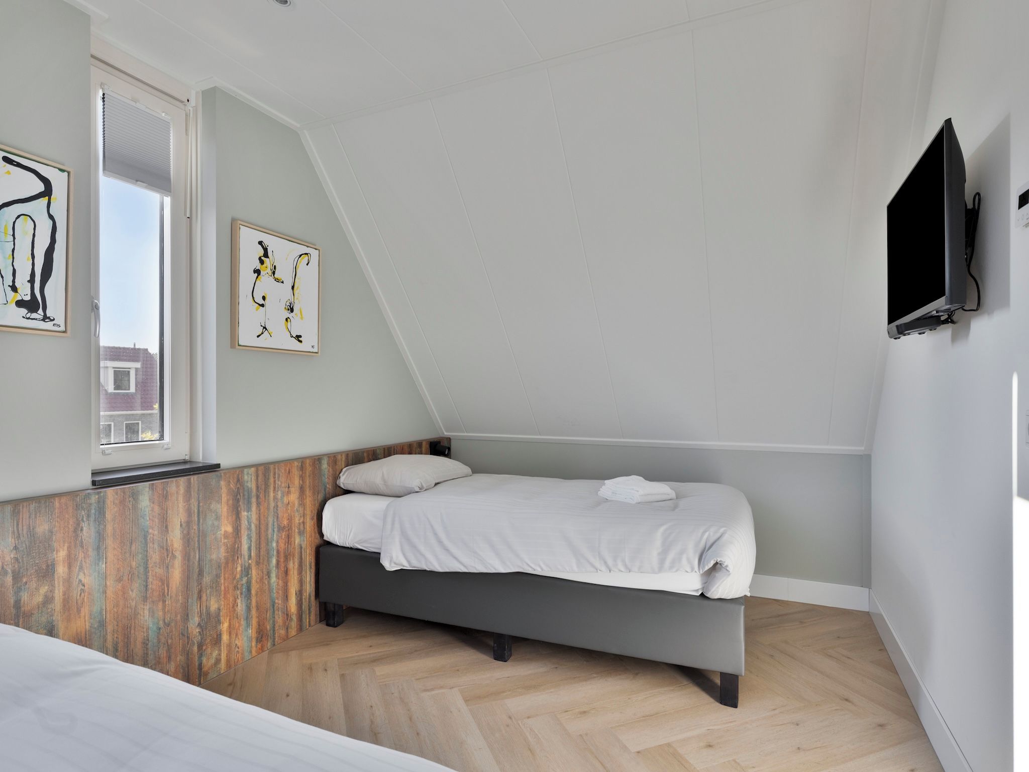 A bedroom with a bed, a window, a painting, and a television.