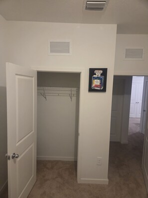 Un couloir avec un placard, une porte et un cadre photo fixé au mur.