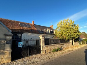 Um edifício com telhado telhado, entrada com portão e placa indicando local de encontro para grupo.