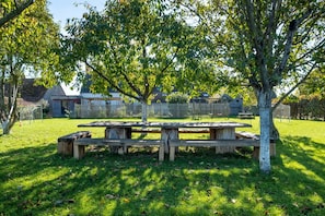 A picnic table set in a grassy area with trees and a fence in the background. - New Listing (Farges-Allichamps)