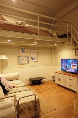 A bedroom with bunk beds, a television, and artwork on the wall. - Haystay Sai Gon Nguyen Van Thu - D1 (Tan Dinh)