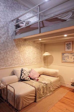 Ein Schlafzimmer mit Etagenbett, Nachttisch, Lampe und einem Bild an der Wand.