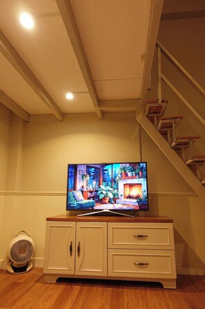 Ein Fernseher steht auf einer Holzkommode in einem Zimmer mit Treppe und Ventilator.