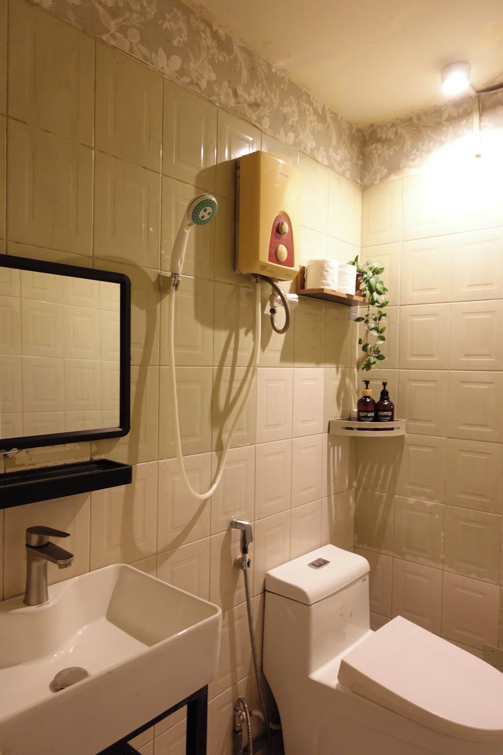 Une salle de bain avec un lavabo, des toilettes et une douche. Il y a un miroir au-dessus du lavabo et une étagère avec des articles de toilette.