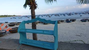 A beach with boats and a blue bench.