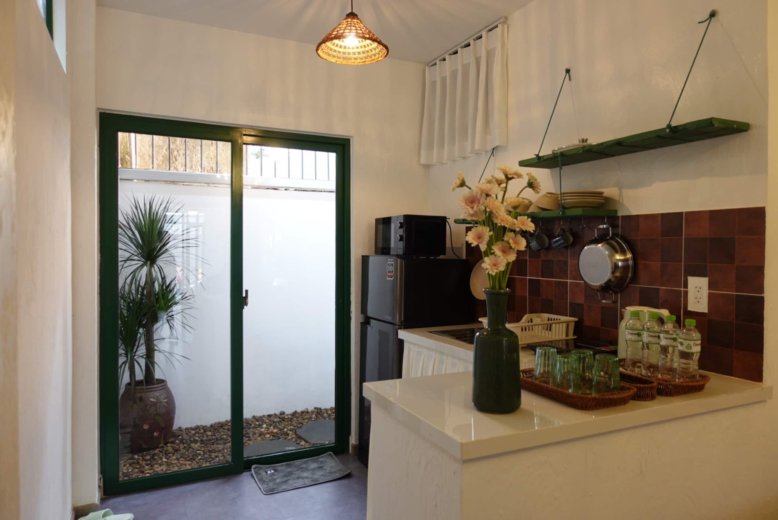 A kitchen with a refrigerator, a sink, a stove, and a hanging pot rack.