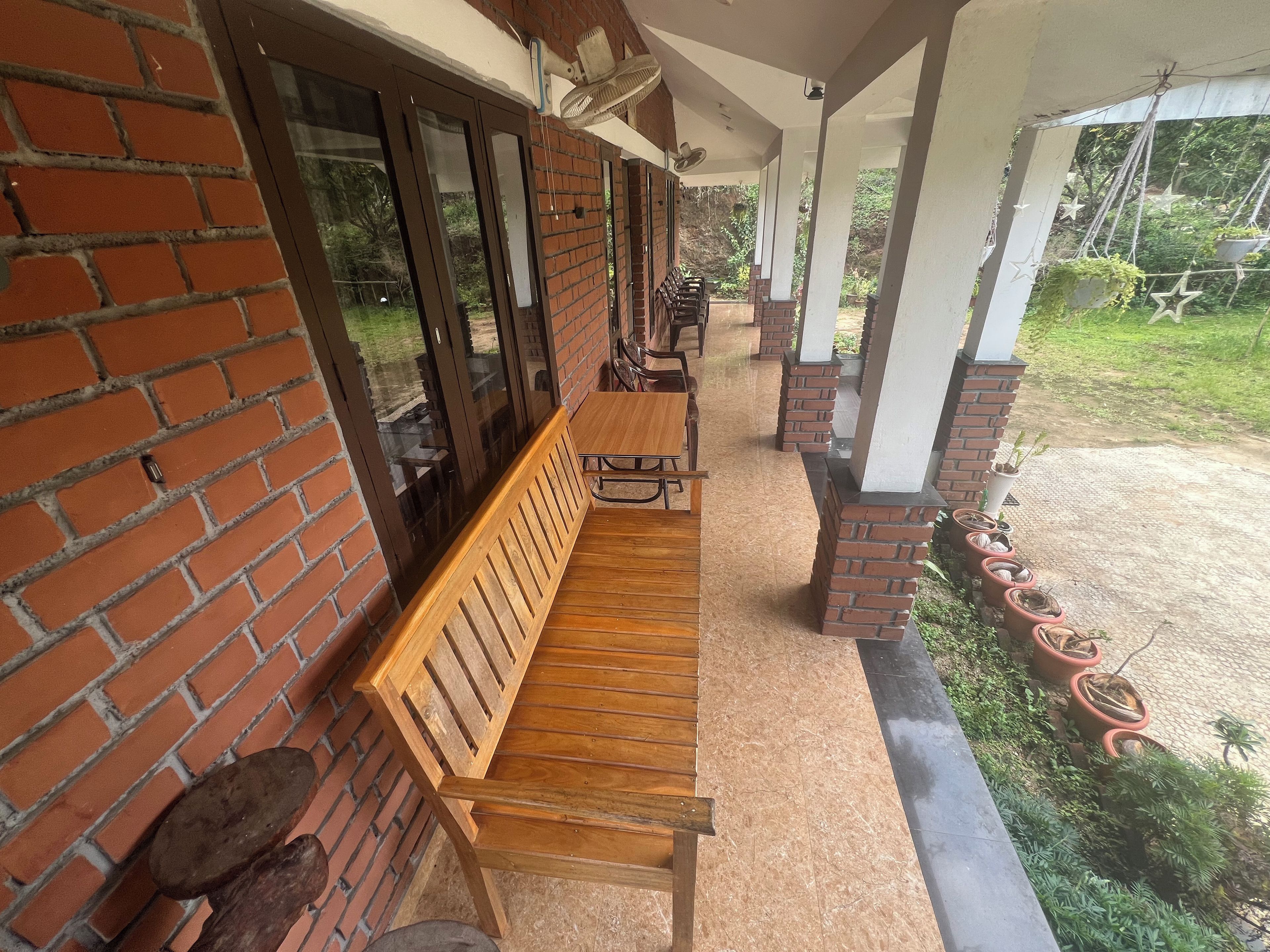 A covered outdoor seating area with a wooden bench and brick walls.