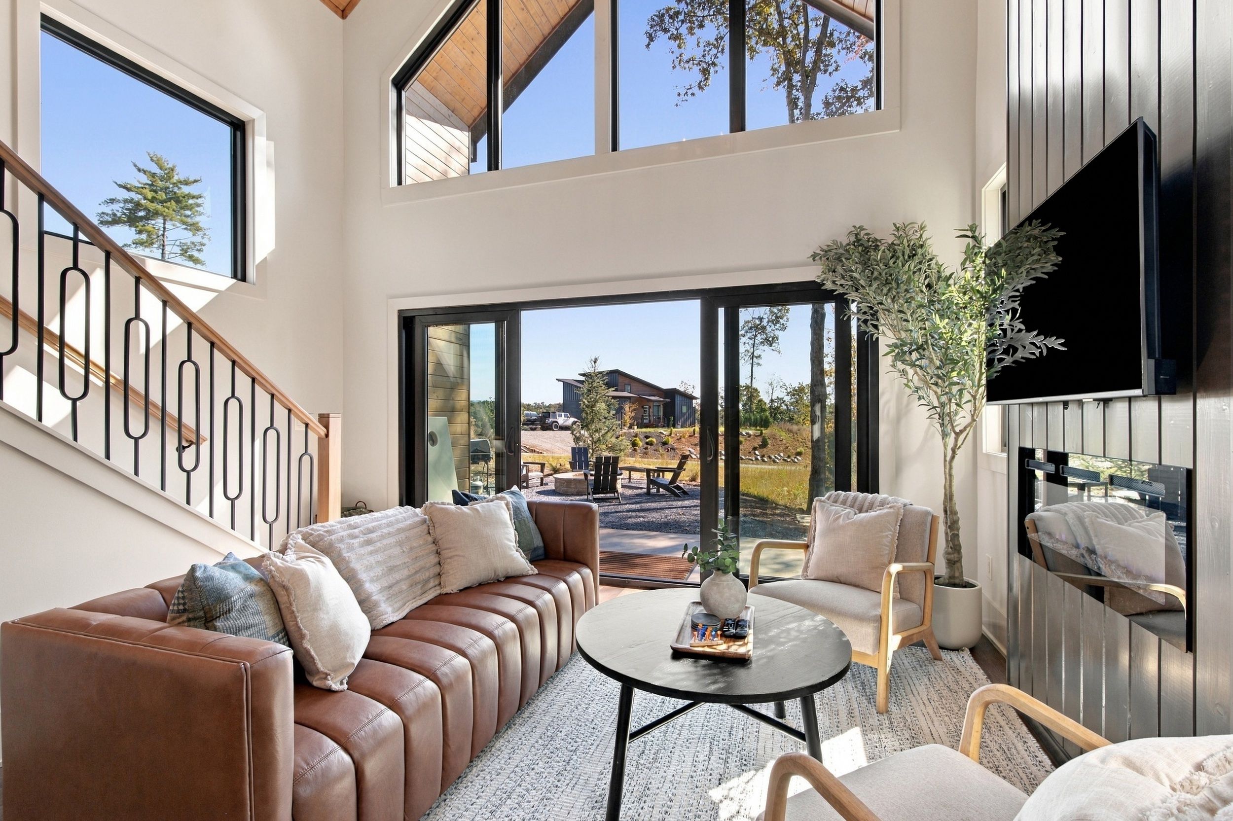 A spacious living area with a leather sofa, a round coffee table, and a television mounted on the wall.
