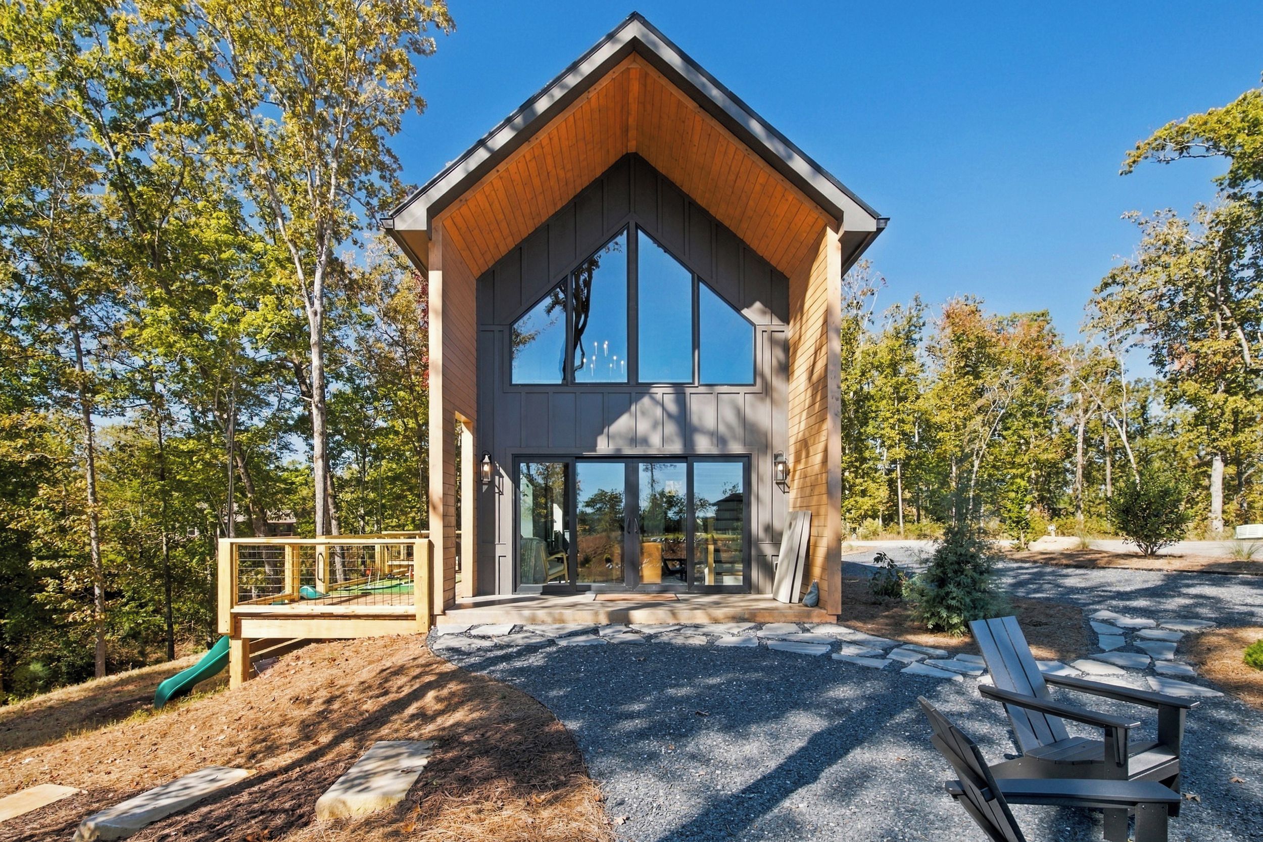 A modern building with a large glass entrance, wooden exterior, and a bench in the foreground.