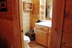 Un baño de madera con inodoro, lavabo y espejo.