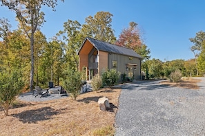A modern house with a gravel driveway, surrounded by trees and a patio with outdoor furniture. - Views, Minigolf, Arcade, Sauna/Hot tub, New Aframe (Ellijay)