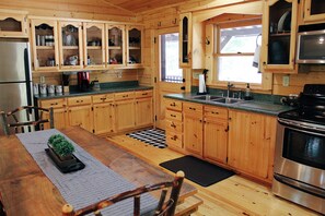 Una cocina de madera con refrigerador, estufa, lavamanos y armarios.