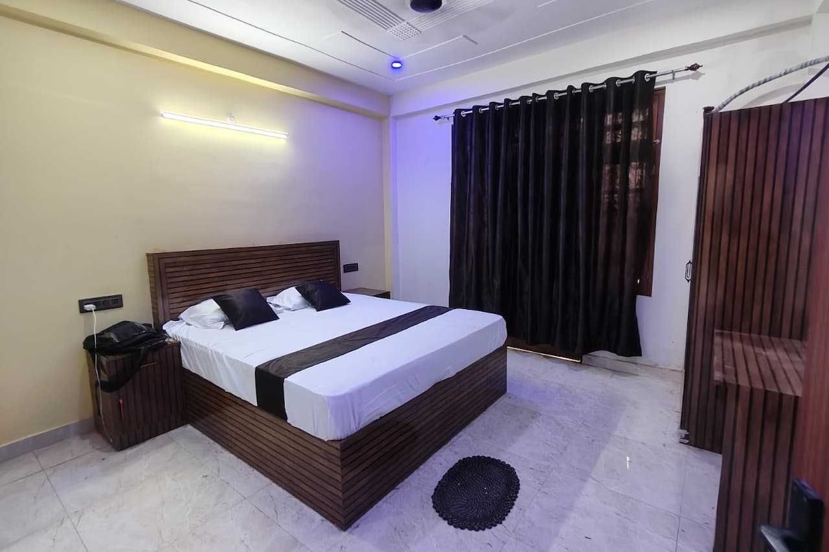 Un dormitorio moderno con una cama grande, una mesita de noche y un ventilador de techo, con una ventana con cortinas.