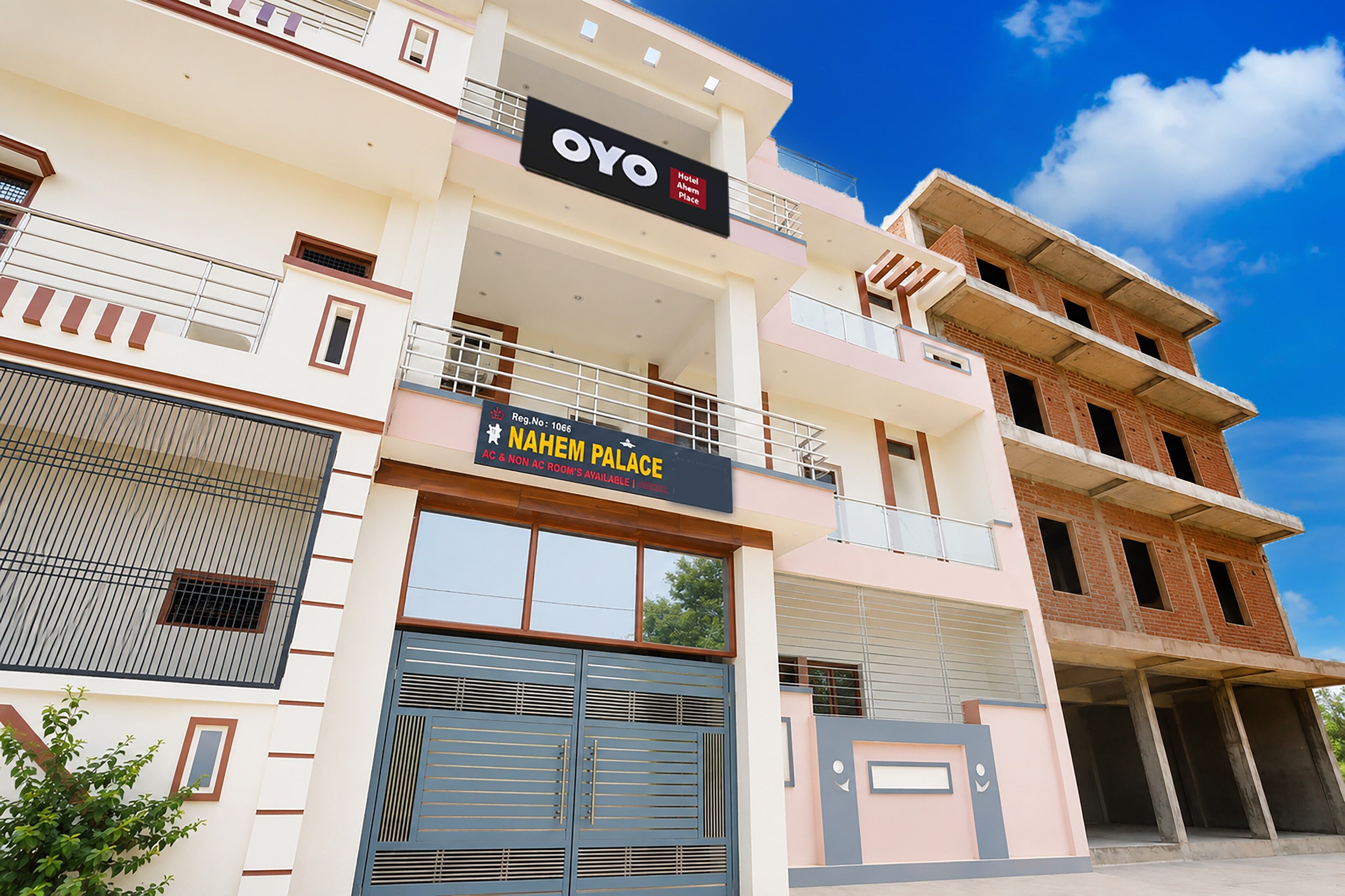 A hotel named 'Oyo Hotel Ahem Palace' with a sign indicating 'NAHEM PALACE' and 'AC & NON AC ROOM'S AVAILABLE'.