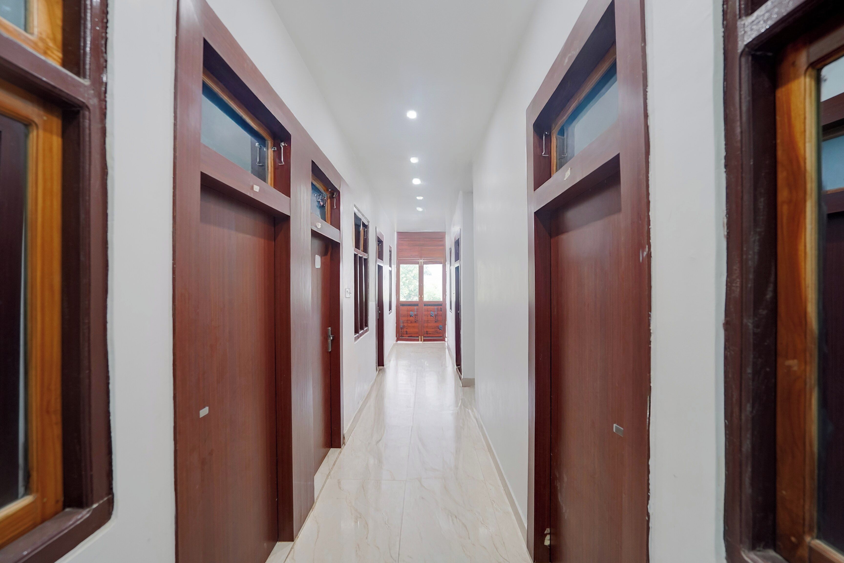 A corridor with wooden doors and windows, leading to a room with a view.