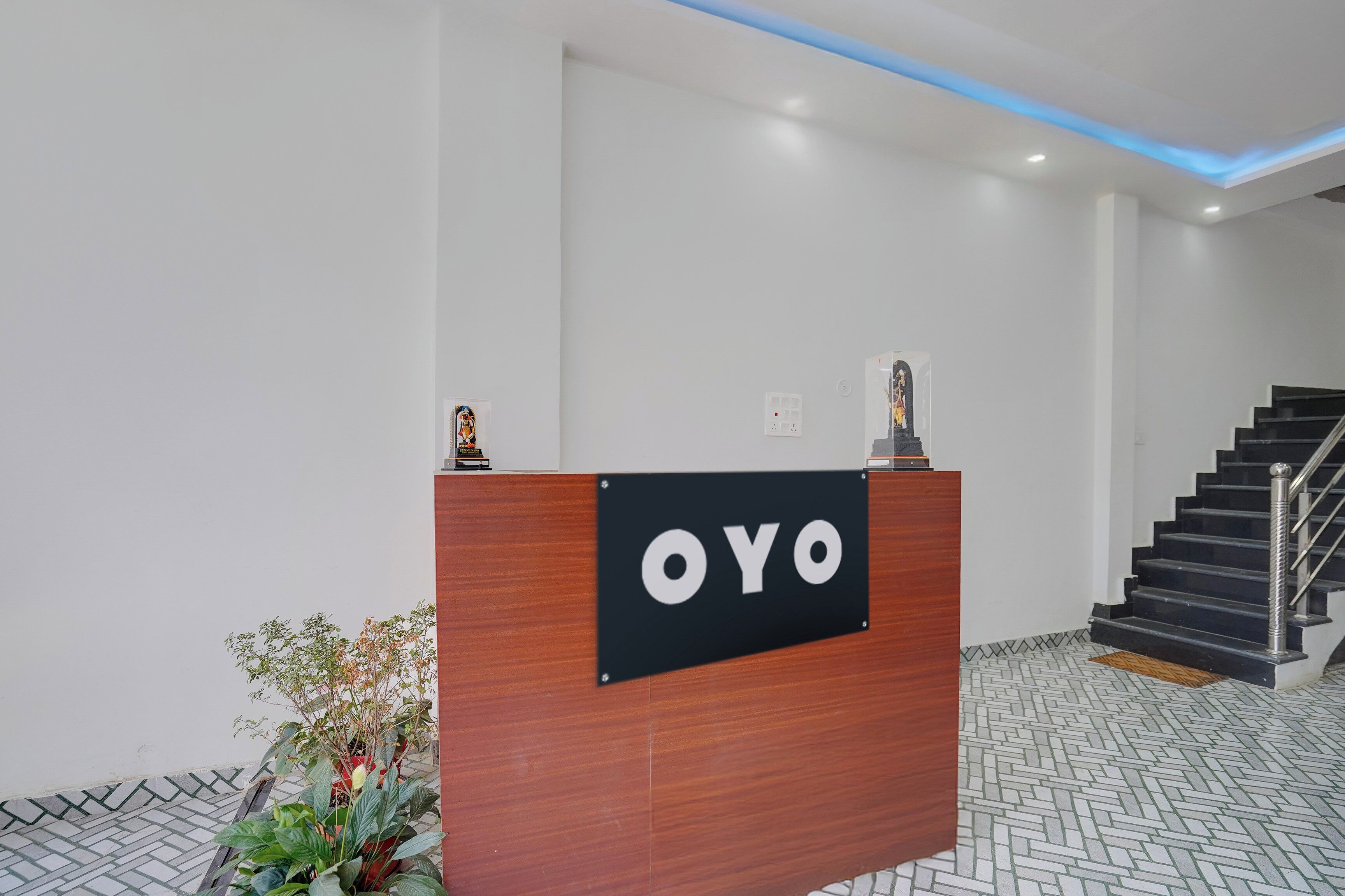 A reception desk with a sign that reads 'OYO' in a modern building with a staircase and patterned flooring.