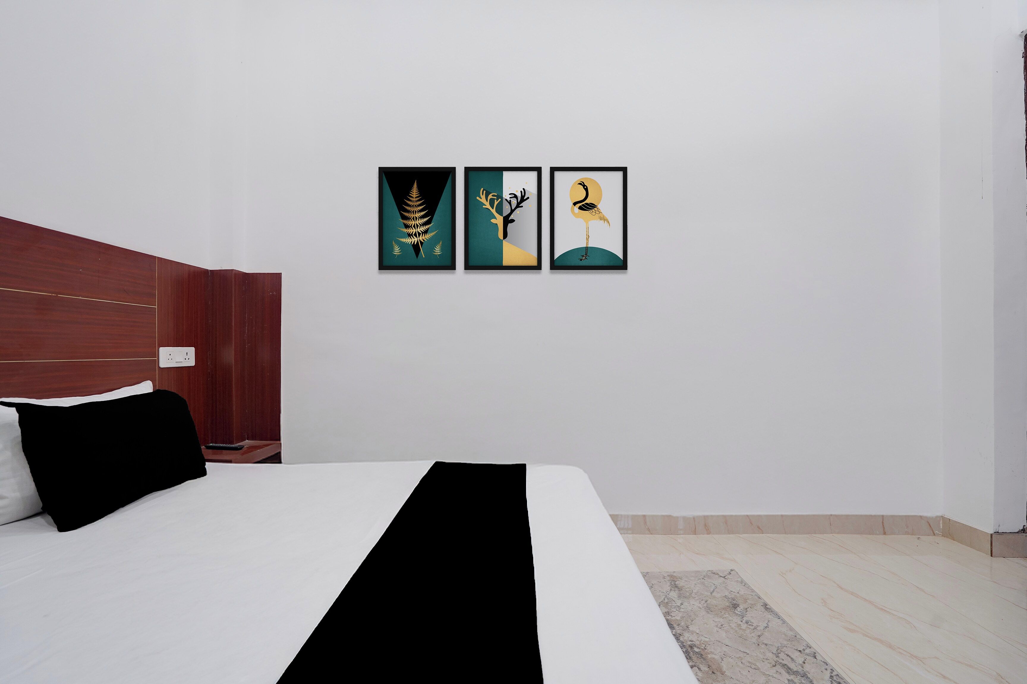 A hotel room with a bed, a wooden headboard, and two framed artworks on the wall.