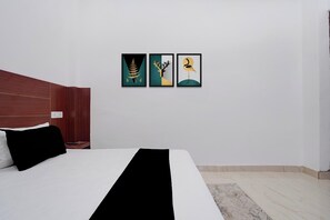 Quarto de hotel com cama, cabeceira de madeira e duas obras de arte emolduradas na parede.