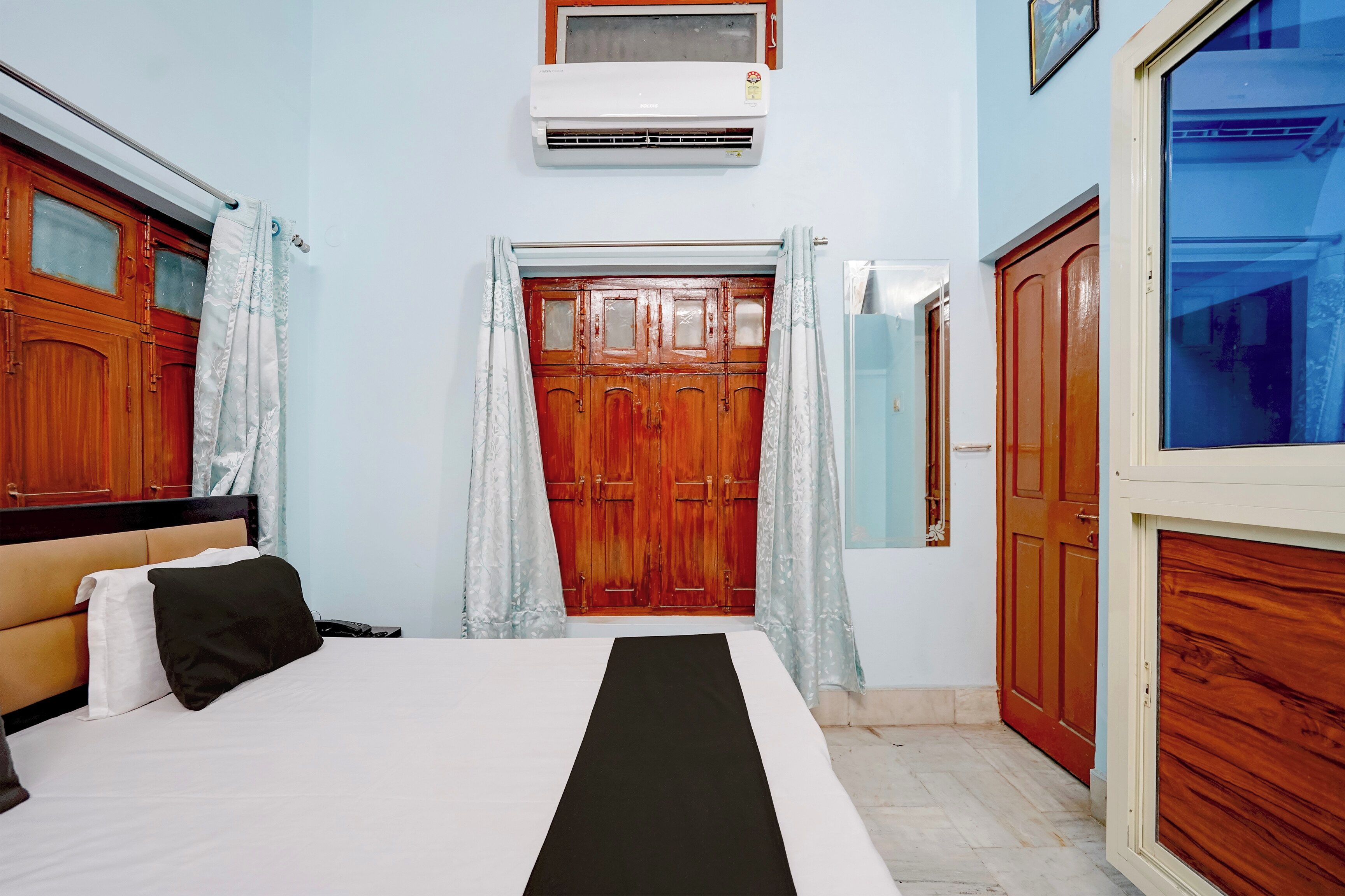 Un dormitorio con cama, armario, ventana y aire acondicionado.