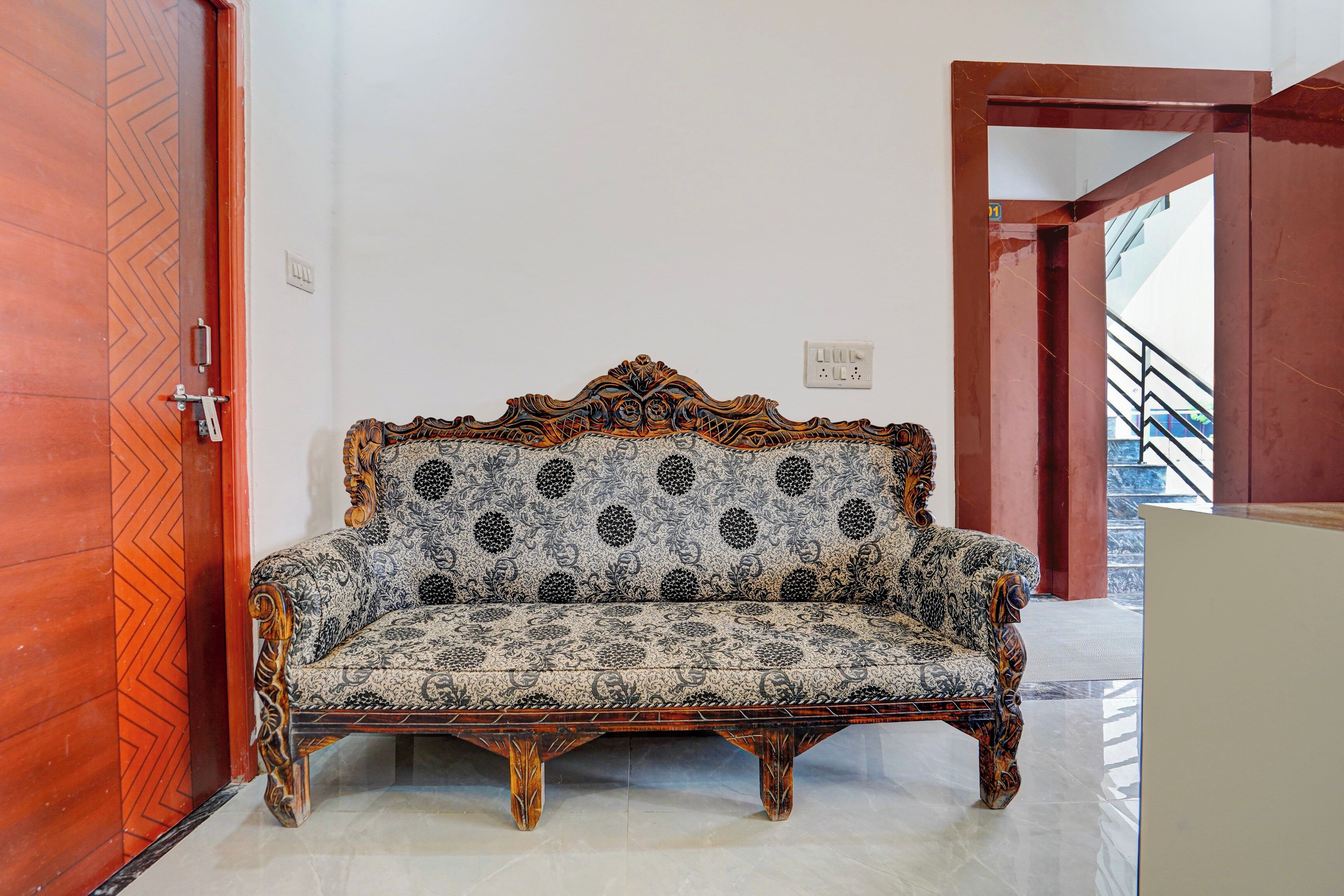 Habitación de esquina con un sofá estampado, una puerta de madera y una escalera.
