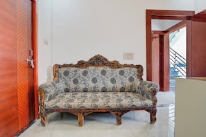 Ein Eckzimmer mit einer gemusterten Couch, einer Holztür und einer Treppe.