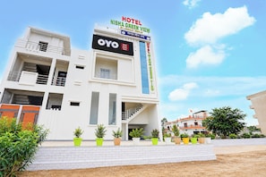 En modern hotellbyggnad med ett framträdande skylt som visar namnet ”Hotel Nisha Green View” och varumärket ”OYO Hotel Nisha Green View”.