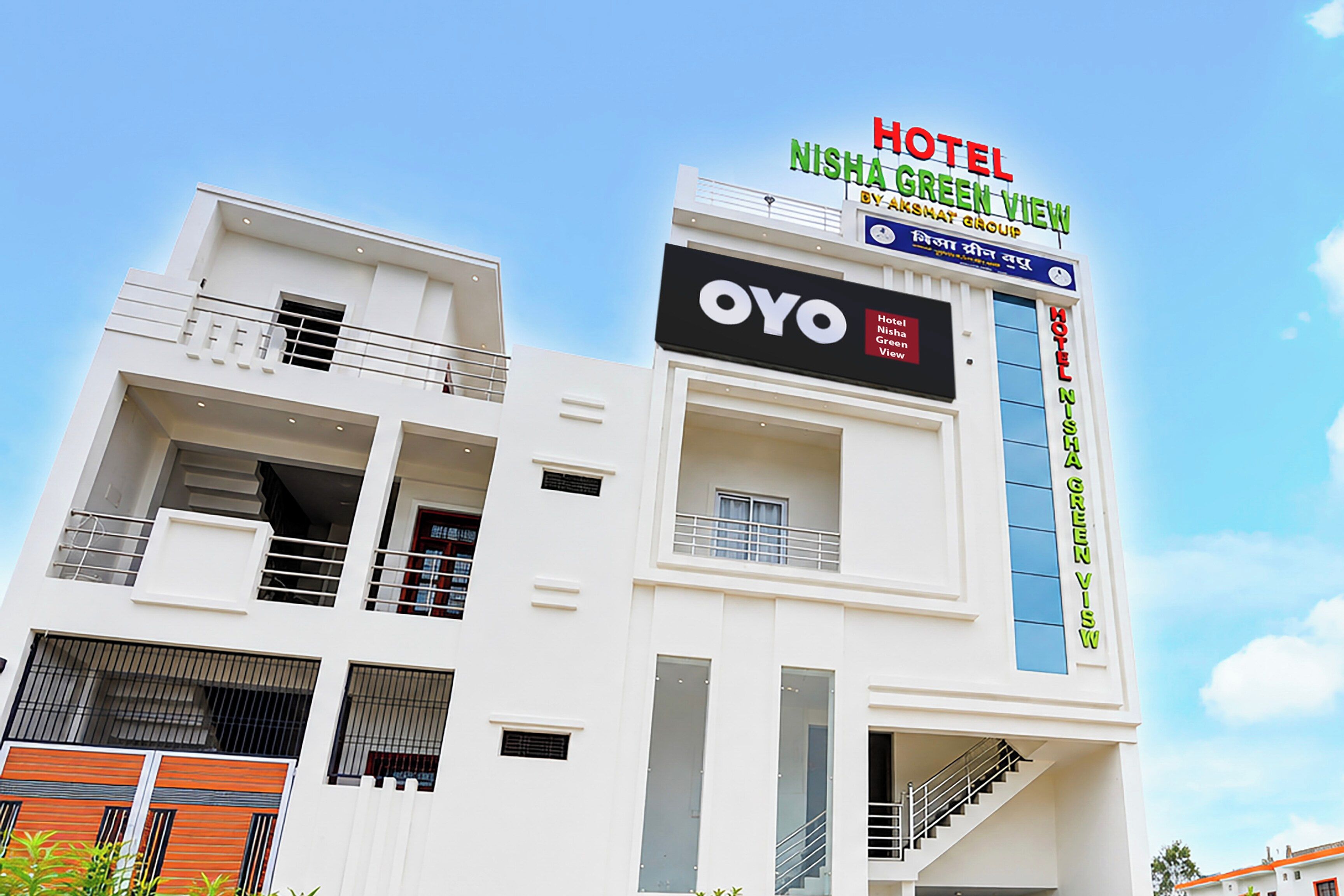 Un edificio de hotel de varios pisos con un cartel llamativo que dice 'HOTEL NISHA GREEN VIEW' y la marca 'OYO'.