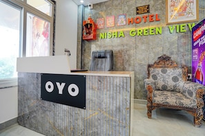 En hotellreception med en skylt som visar texten ”OYO” och en stol med detaljerade mönster.