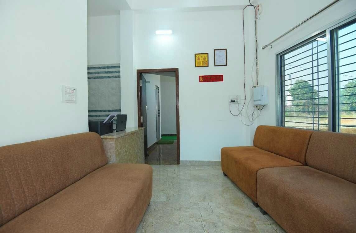 A waiting area with two sofas, a reception desk, and a window with blinds.