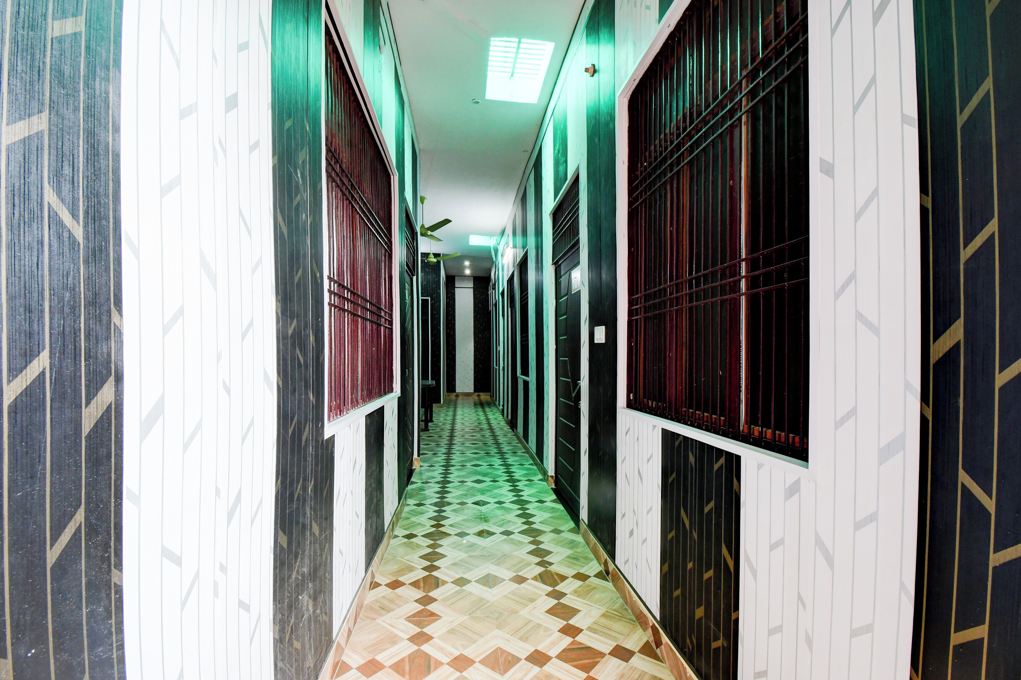 A corridor with patterned walls and doors, leading to a room with a ceiling fan.