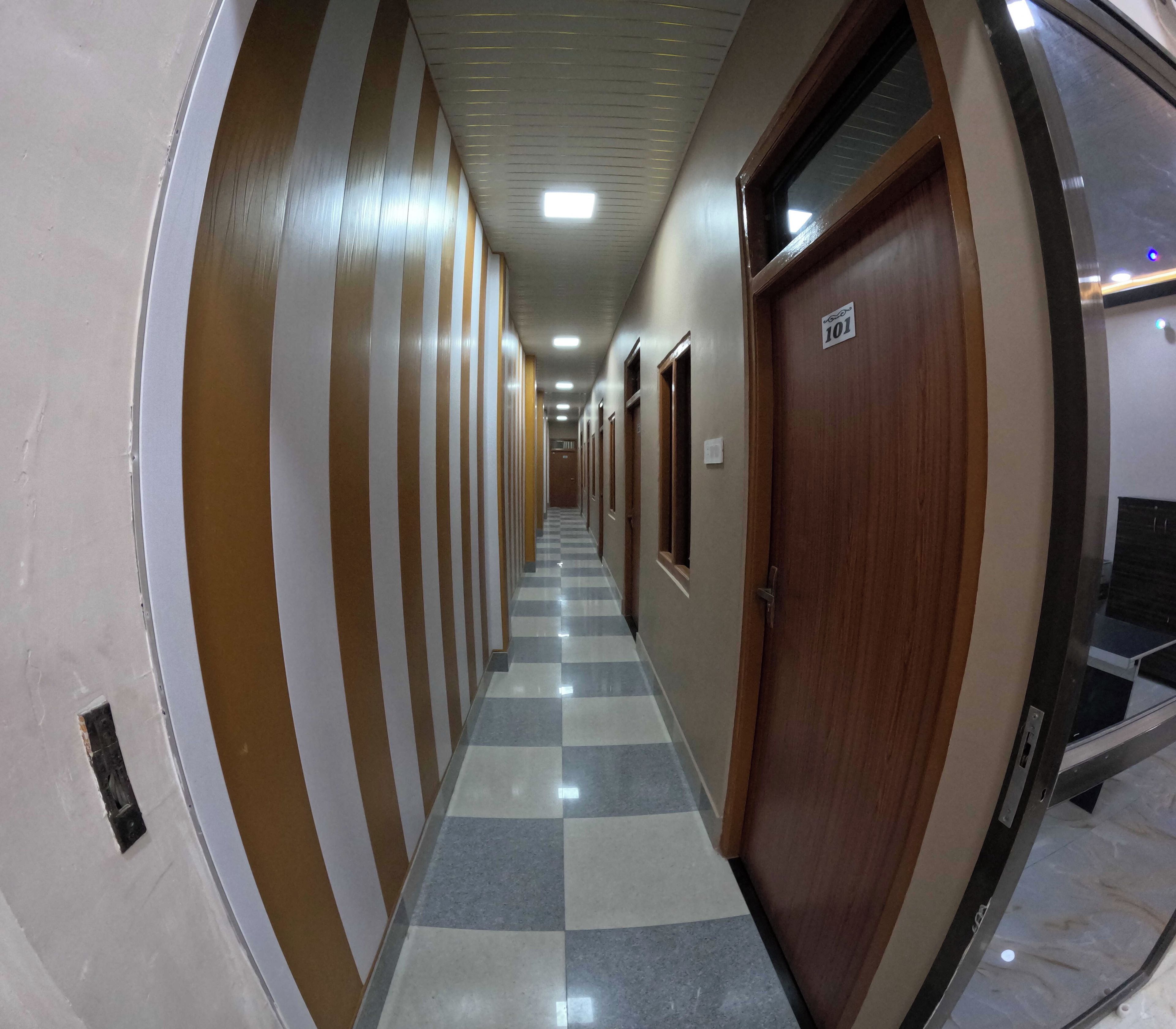 A corridor with a checkered floor, striped walls, and a door marked with the number 101.
