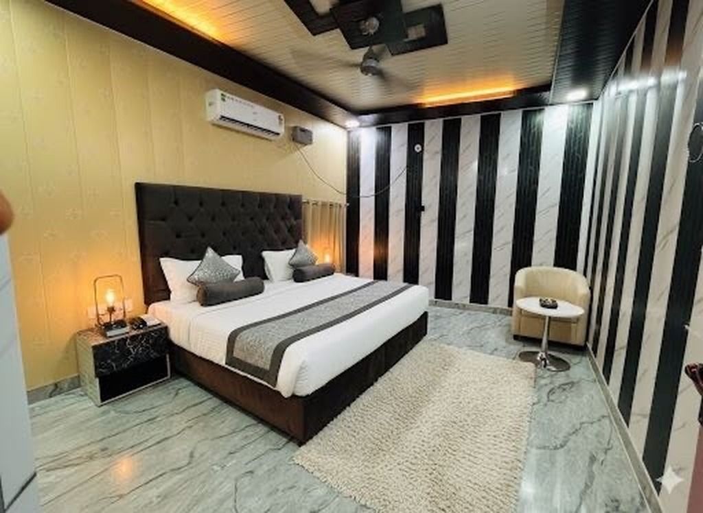 A bedroom with a large bed, a bedside table, a chair, and a wall-mounted air conditioner.