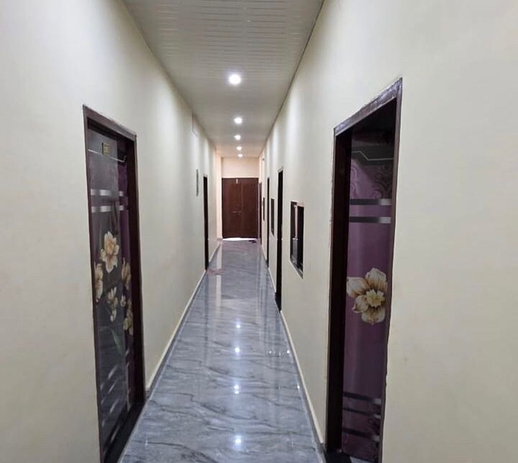 A corridor with doors on either side, a marble floor, and a ceiling with recessed lighting.