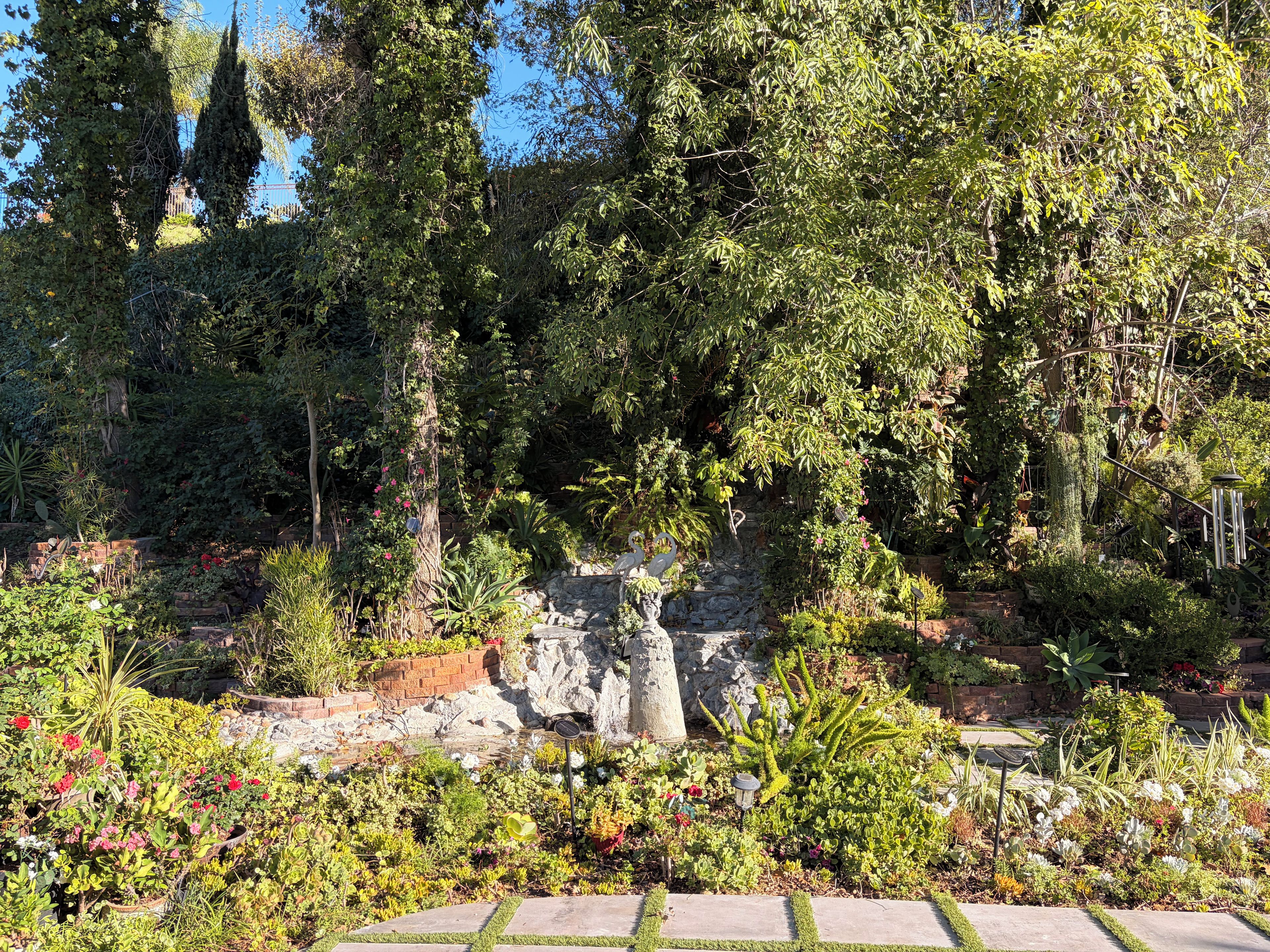 Un jardin où l’on trouve une grande variété de plantes et une structure en pierre.
