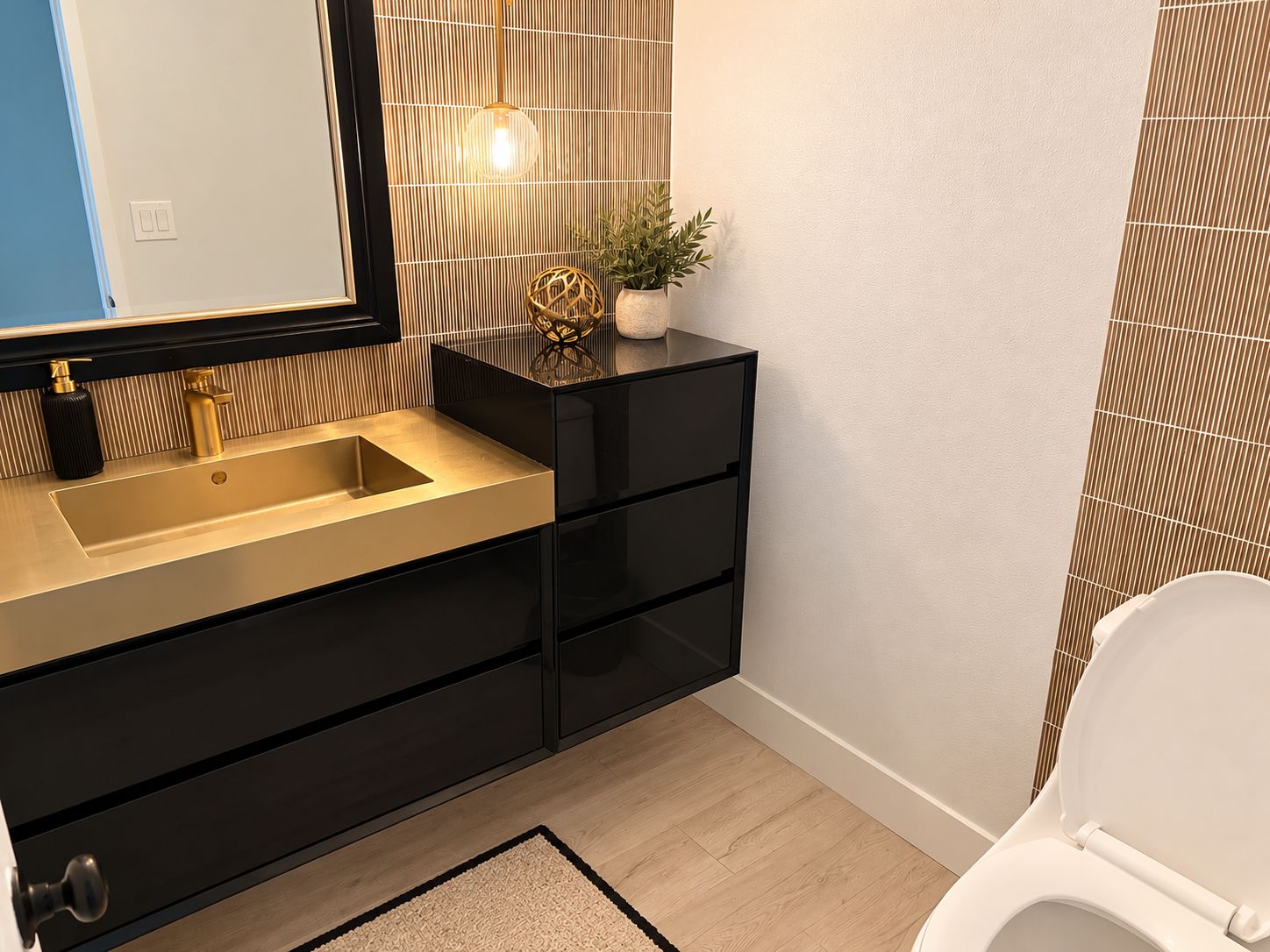 Une salle de bain moderne avec un meuble-lavabo noir, un évier doré et des toilettes blanches.
