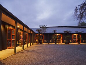 A modern building with a gravel courtyard, large windows, and outdoor seating. - 27 Cron Street (Franz Josef/Waiau)