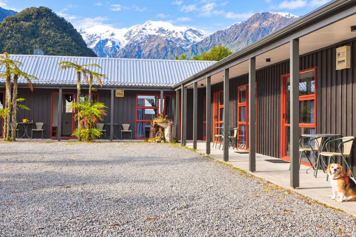 A building with a gravel courtyard, outdoor seating, and a mountain backdrop.