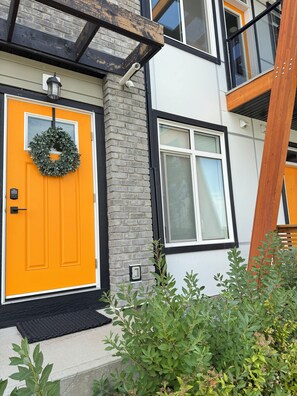 Un edificio con fachada de ladrillo, una puerta de color naranja brillante y una ventana con marco blanco.