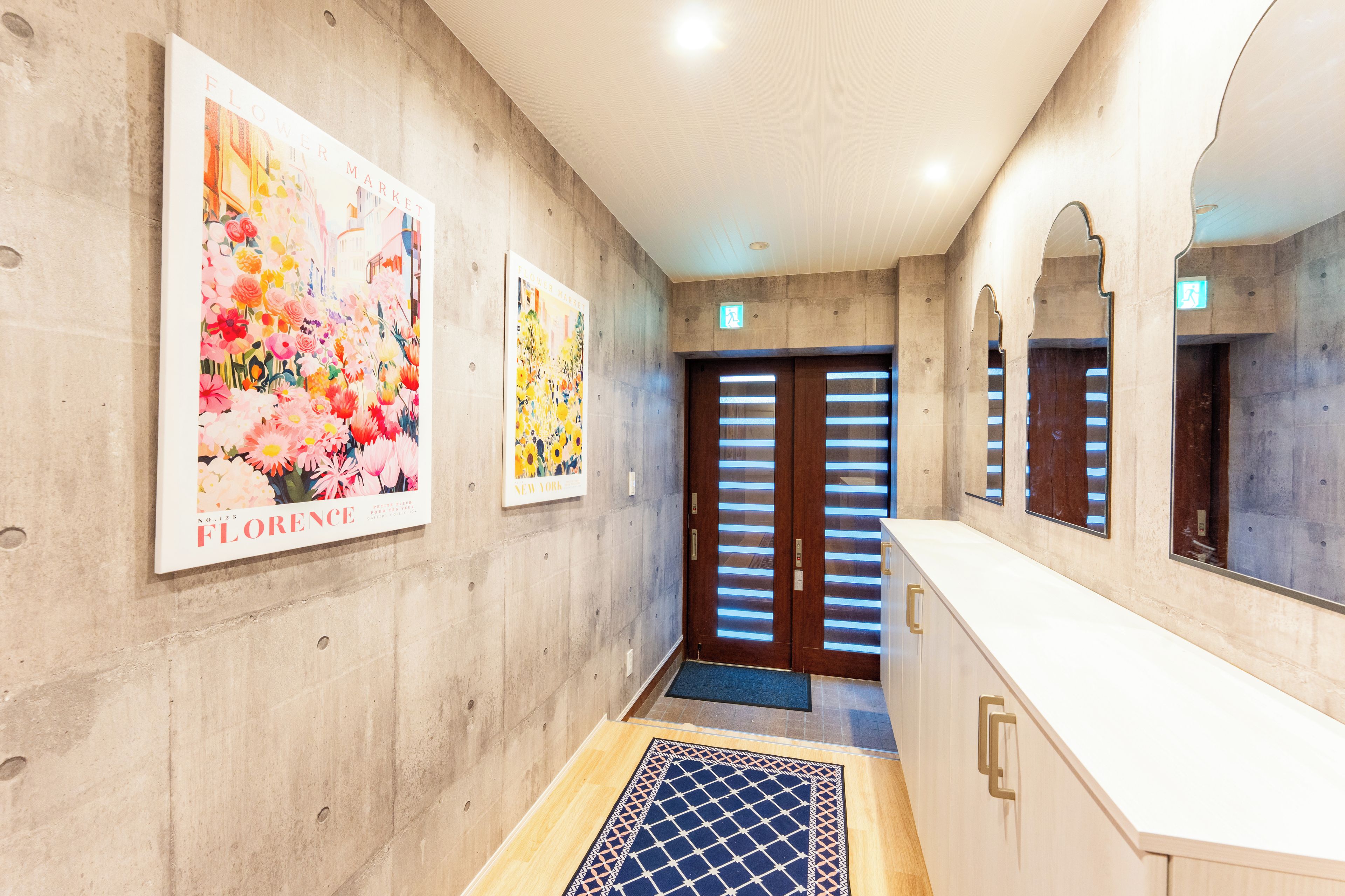 A hallway with a wooden floor, a reception desk, and two doors with blinds.