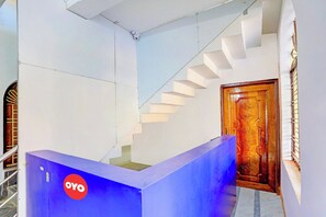 Un escalier, un comptoir d’accueil bleu et une porte en bois ornée de motifs floraux.