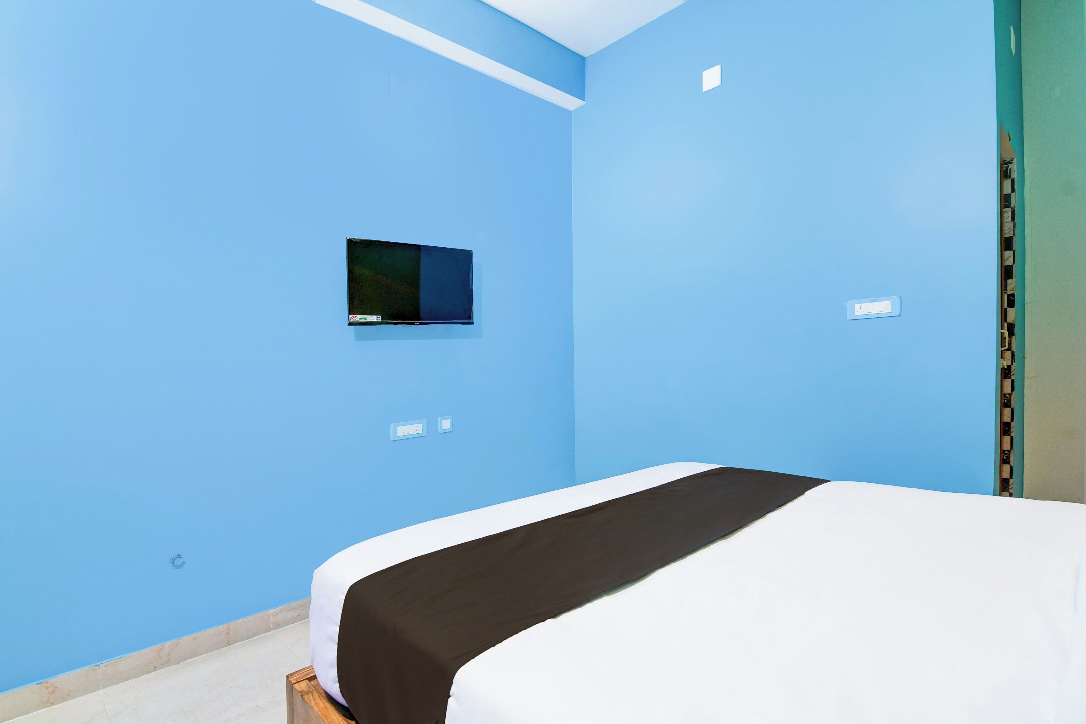 A room with a bed, a small TV mounted on the wall, and a power outlet.