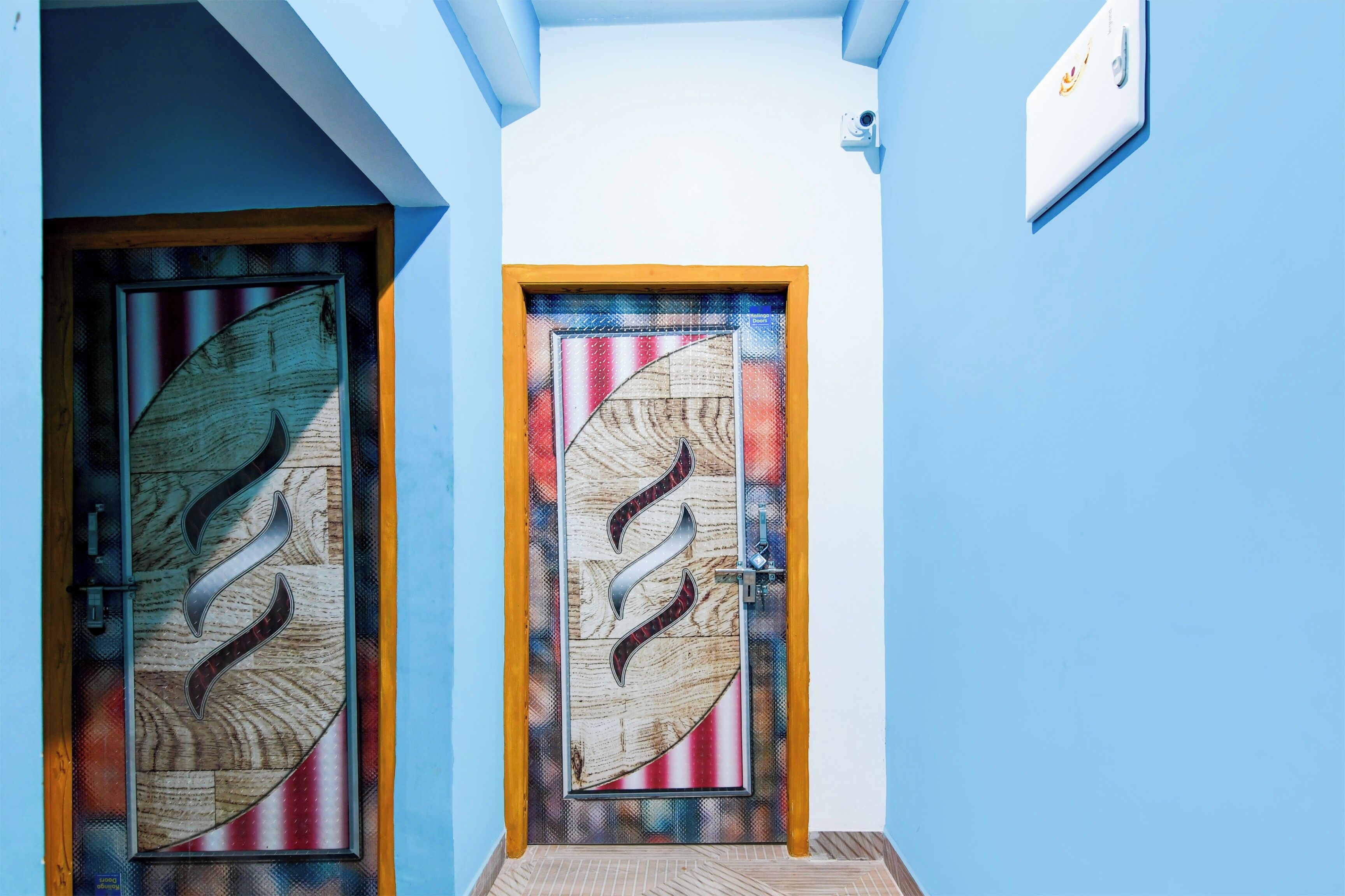 Two doors with intricate designs, one with a leaf pattern and the other with a circular motif, both framed in wood and set against a blue wall.