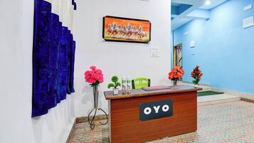 A reception desk with a sign reading 'OYO' in a hotel lobby with a blue wall and a painting of horses.
