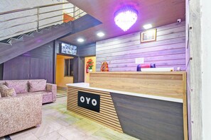 A reception area with a wooden desk, a sofa, and a staircase.