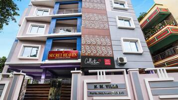 A multi-story hotel with balconies, a sign for 'Secret Heaven A/C & Non-A/C Room,' and a 'Collection' sign.