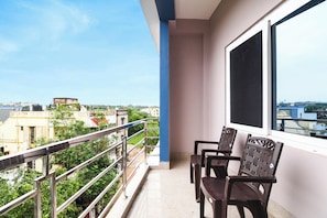 Un balcón con vistas a un paisaje urbano, una ventana y dos sillas.