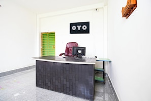 Uma mesa de recepção com um computador, uma cadeira e uma placa com a inscrição 'OYO'.