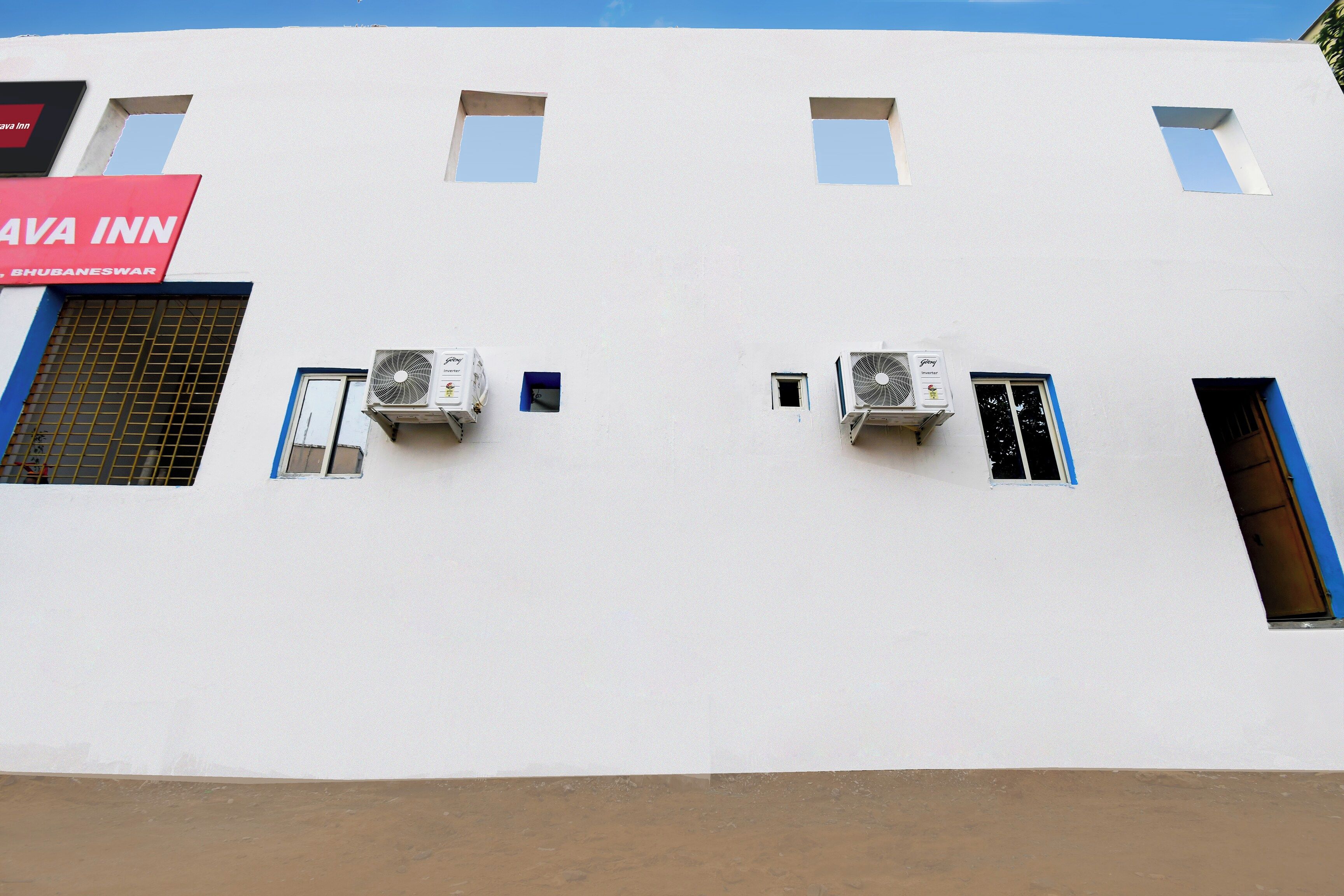A building with multiple windows and air conditioning units mounted on the exterior wall.