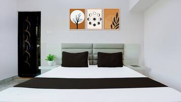A modern bedroom with a bed, two pillows, a bedside table, a potted plant, and three wall art pieces.