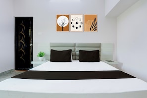 Un dormitorio moderno con cama, dos almohadas, una mesita de noche, una planta en maceta y tres cuadros en la pared.